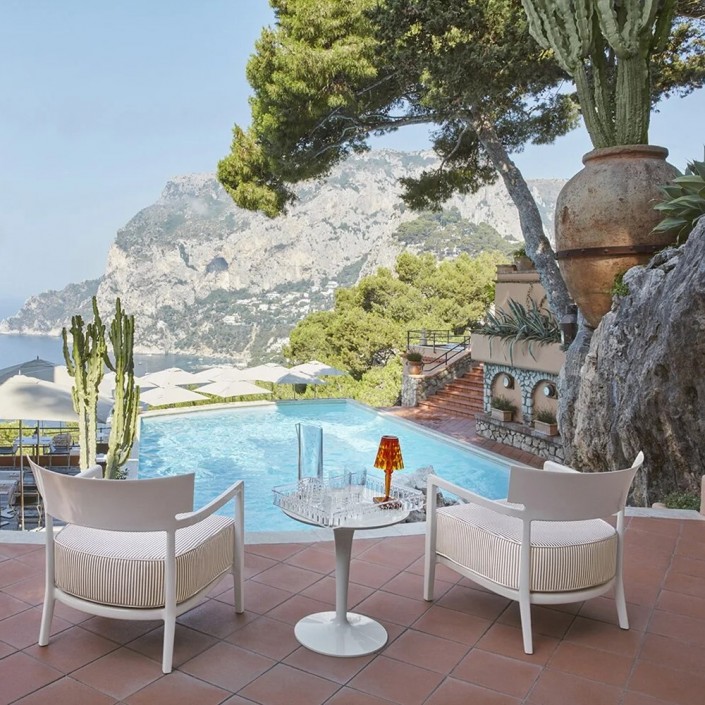 Fauteuil CARA OUTDOOR IVOIRE/FIBRE TEINTÉE BEIGE Kartell - Valente Design - sur terrasse vue piscine