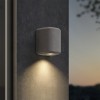 Applique d'extérieur Brixham Wall Single d'Astro Lighting finition béton gris allumée sur un mur extérieur de nuit