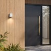 Applique d'extérieur Brixham Wall Single d'Astro Lighting finition béton blanc allumée dehors à côté d'une porte de jour