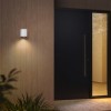 Applique d'extérieur Brixham Wall Single d'Astro Lighting finition béton blanc allumée dehors à côté d'une porte de nuit