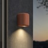 Applique d'extérieur Brixham Wall Single d'Astro Lighting finition béton terracotta allumée sur un mur extérieur de nuit