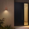 Applique d'extérieur Brixham Wall Single d'Astro Lighting finition béton terracotta allumée dehors à côté d'une porte de nuit