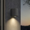 Applique d'extérieur Brixham Wall Single d'Astro Lighting finition béton charbon allumée sur un mur extérieur de nuit