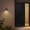 Applique d'extérieur Brixham Wall Single d'Astro Lighting finition béton gris allumée dehors à côté d'une porte de nuit