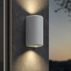 Applique d'extérieur Brixham Wall Twin d'Astro Lighting finition béton blanc allumée sur un mur extérieur de nuit