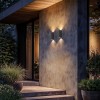 2 appliques d'extérieur Brixham Wall Twin d'Astro Lighting finition béton charbon allumées sur un mur extérieur de nuit